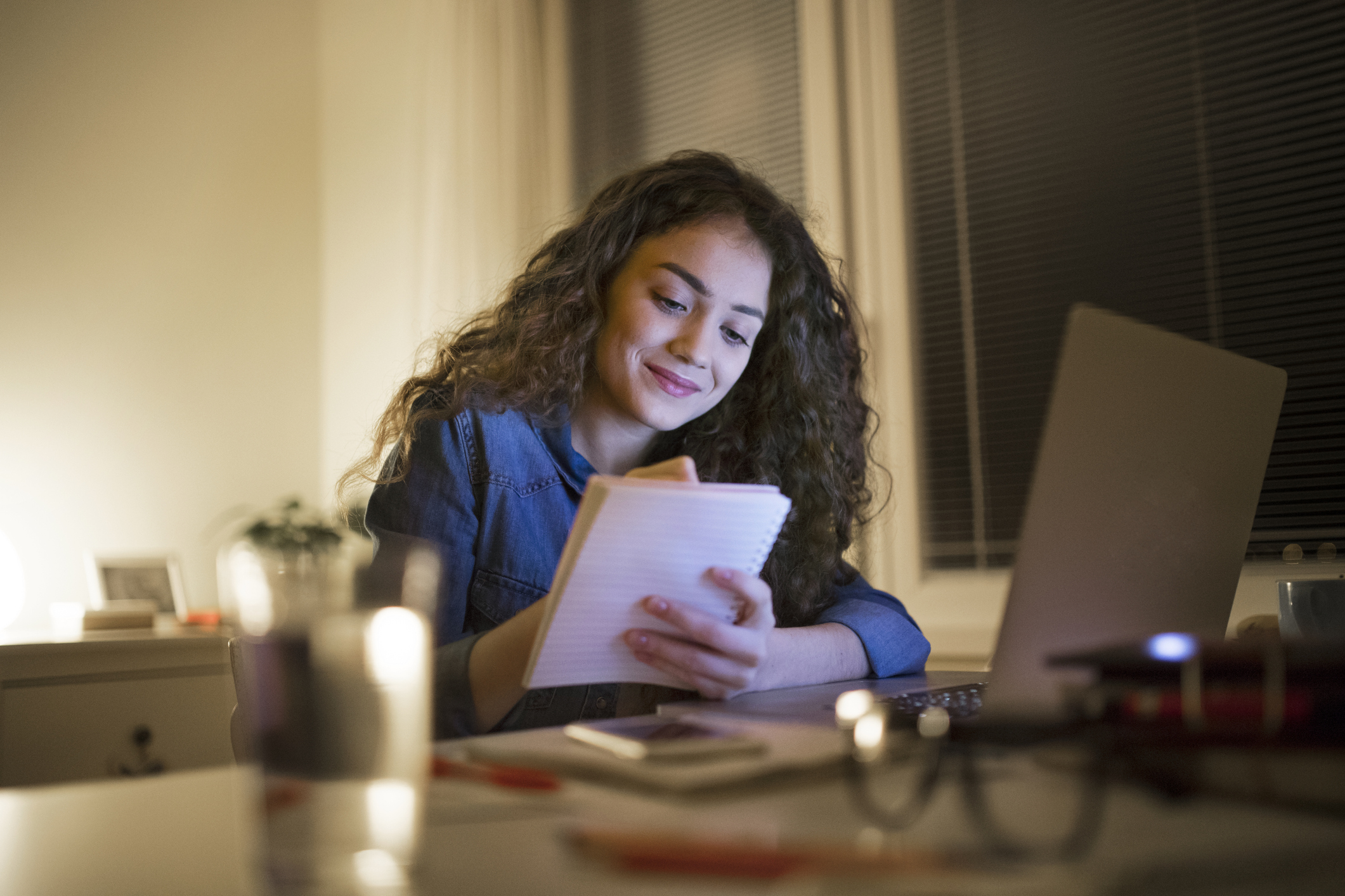 A young woman studying with a notebook and a laptop